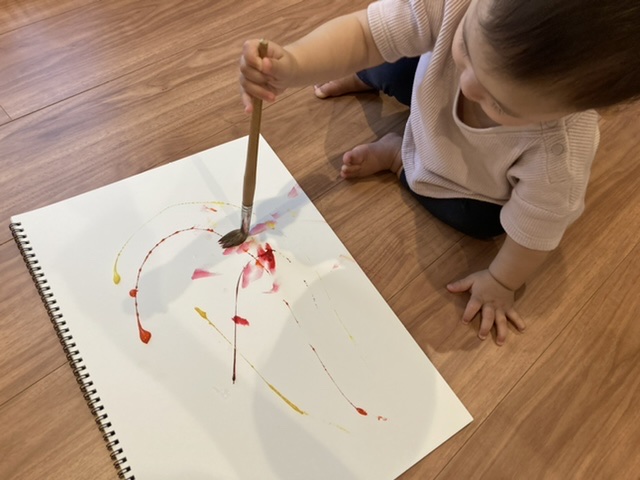 筆で絵の具を塗る0歳児
