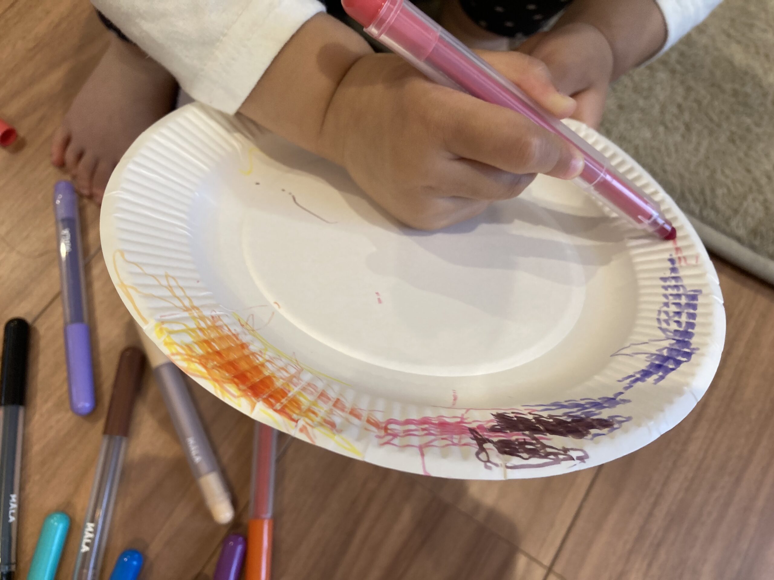 紙皿に色を塗る2歳児